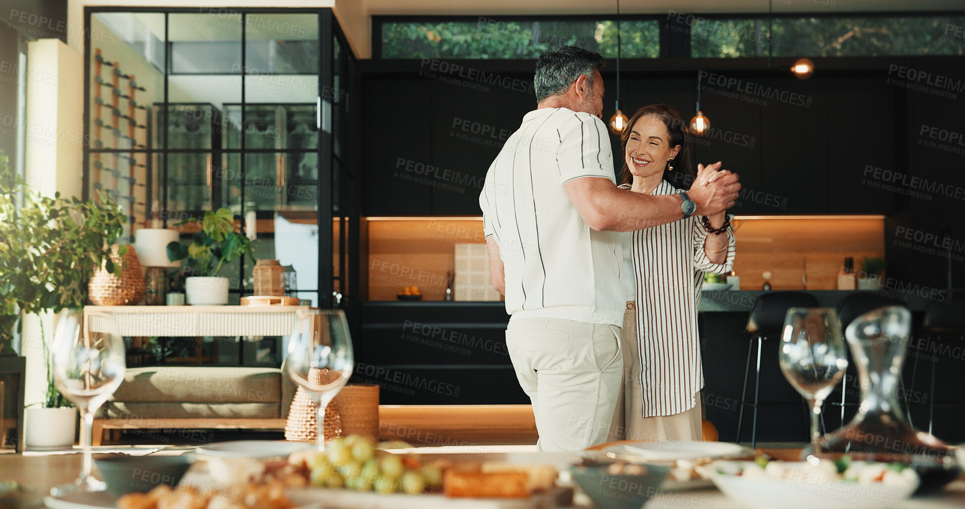 Buy stock photo Care, dance and mature couple in home for romantic commitment, holding hands and smile together. Happy man, woman and moving to music for marriage connection, partner support and love at dinner