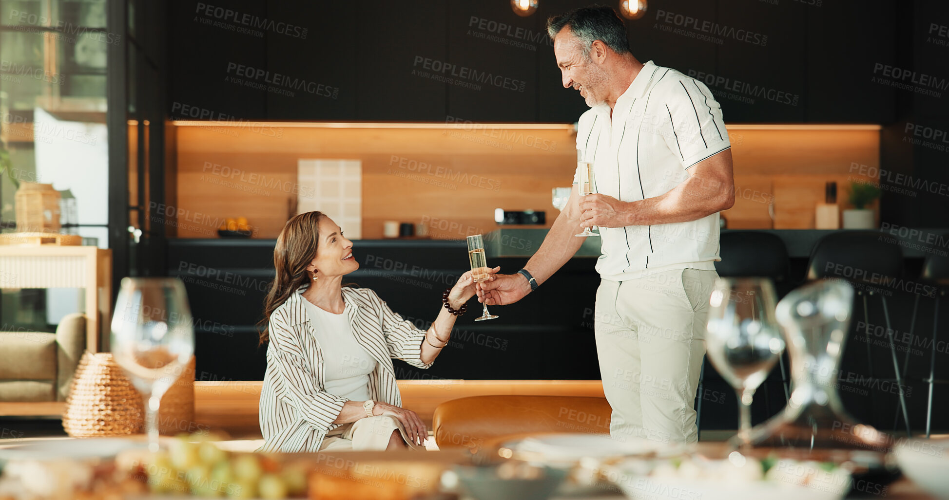 Buy stock photo Couple, home and laughing with champagne, love and bonding with partner in lounge or relax together. Relationship, anniversary and happy mature people with alcohol, commitment and connection in house