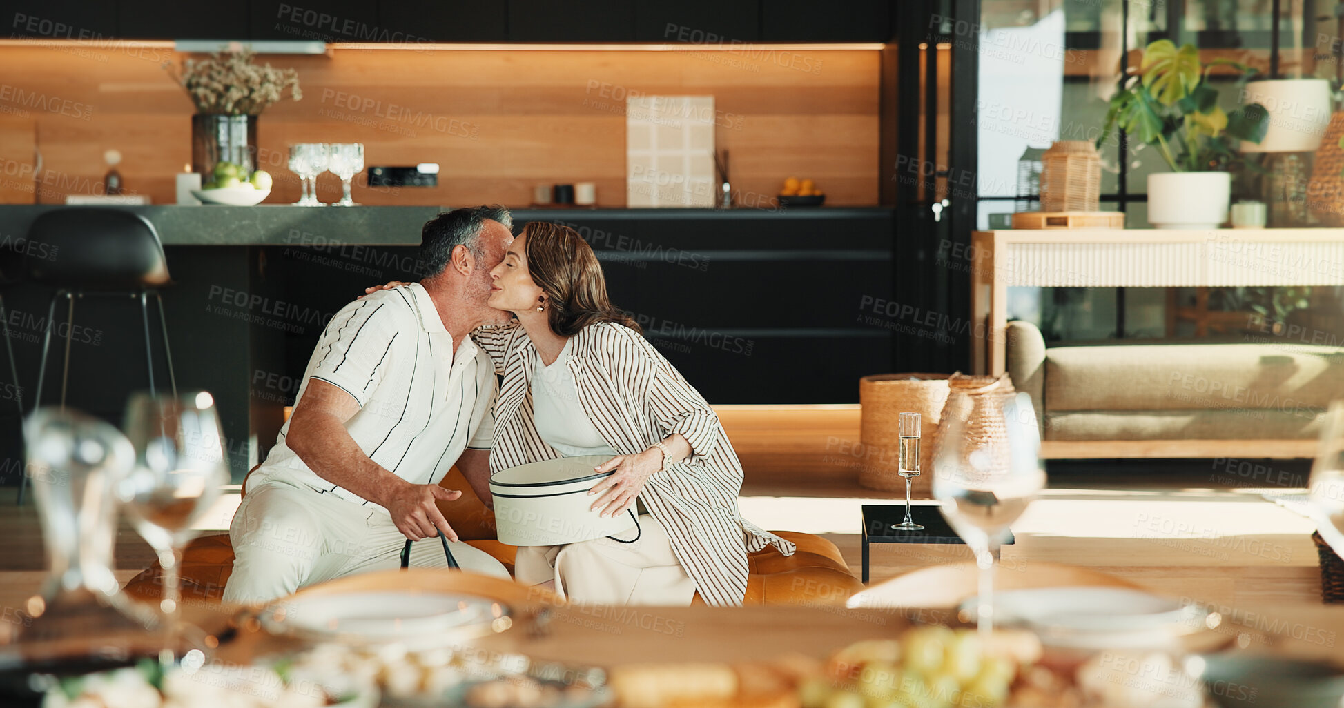 Buy stock photo Love, hug and couple with gift in home, valentines day or gratitude for anniversary celebration. Man, mature woman and embrace with present appreciation, care or marriage milestone at romantic dinner