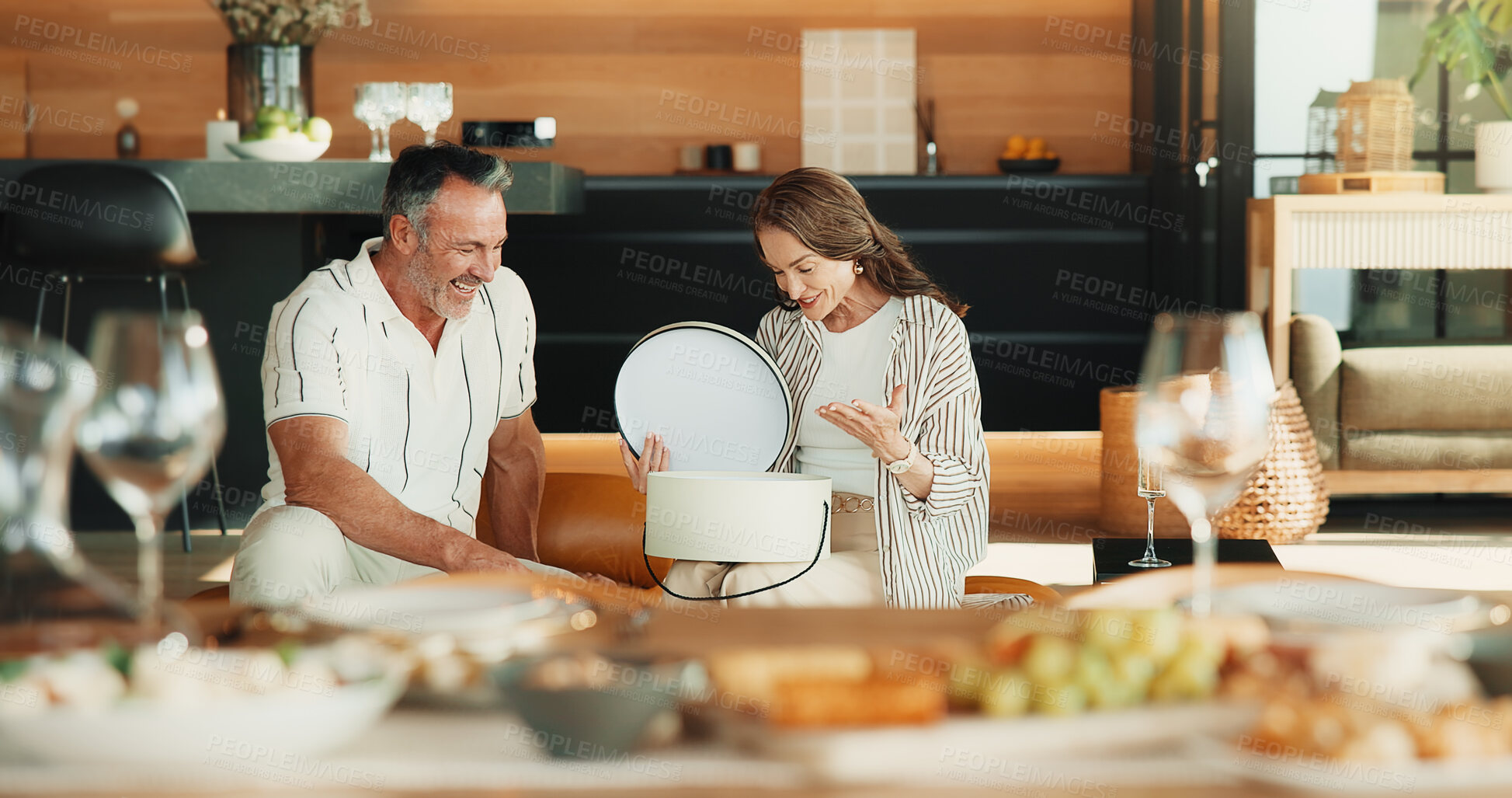 Buy stock photo Love, present and mature couple in home, laugh and gratitude for Christmas celebration with smile. Man, woman or surprise gift, thank you and xmas holiday with funny partner at romantic dinner