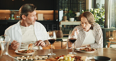 Buy stock photo Couple, lunch and conversation at dining table with wine, relax together and gossip on weekend break. Mature people, date and eating spaghetti food in home with alcohol drink, bonding and discussion.