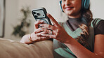 Woman, hands and headphones in home with phone, social media and streaming music on platform. Person, mobile and smile in living room for unique playlist, connectivity and update app subscription