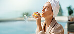 Alcohol, hotel and woman with drink by pool for vacation, luxury getaway and holiday on weekend. Hospitality, travel and person with mimosa, towel and juice for tourism, relax and break at resort