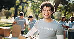 Volunteer, portrait and man with box in park for outreach program, community service and welfare. Happy, outdoor and person with package for food drive, donation and charity event for ngo campaign
