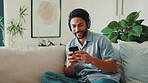 Man, happy and headphones or phone on home sofa for streaming music, podcast or online subscription. Smile, audio playlist and male person relax on couch with mobile app, technology and sound