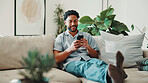 Happy, man and browsing in living room with phone, social media app and relax on calm weekend break. Person, smile and typing in home with tech, entertainment and internet for digital communication.