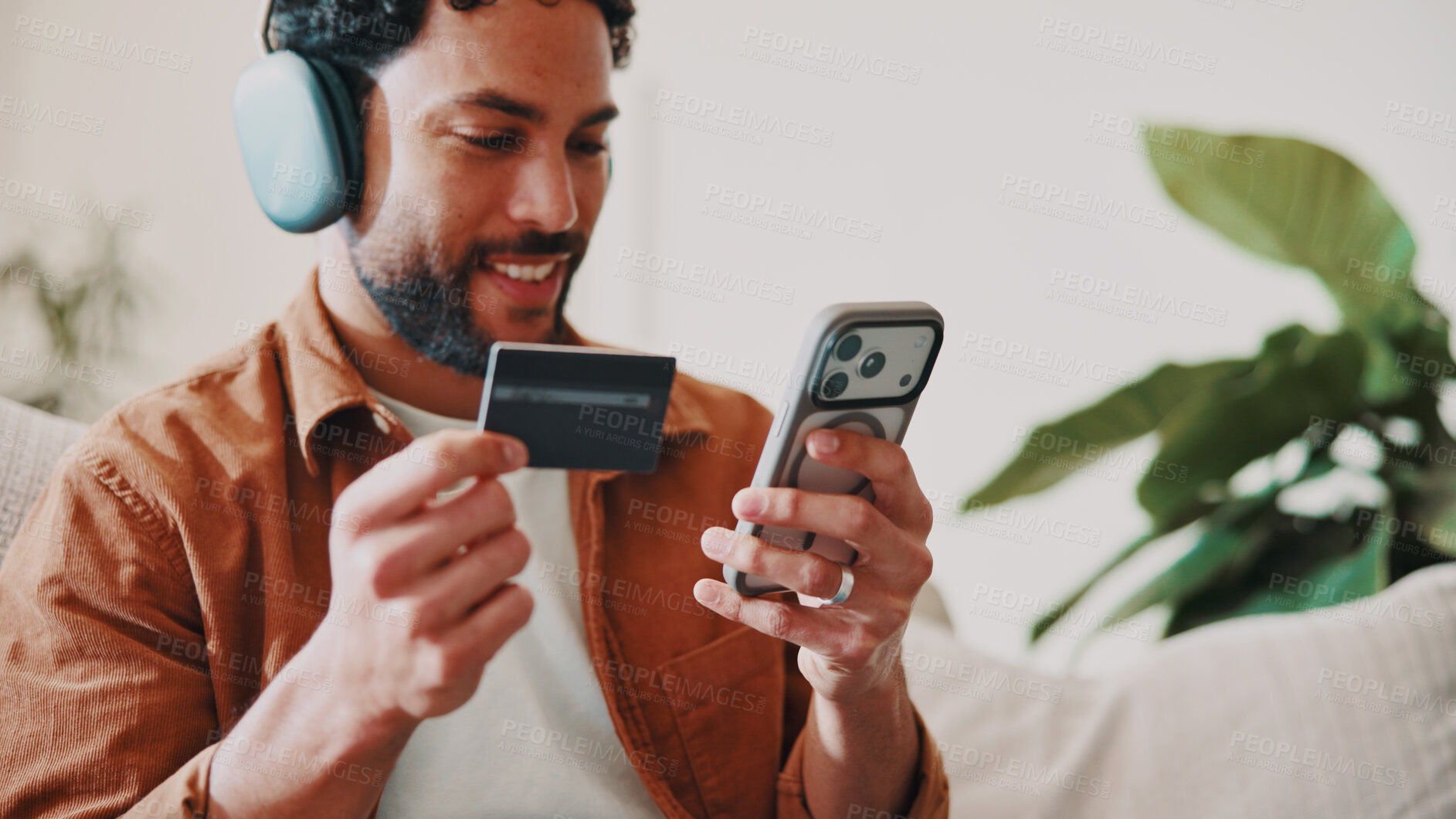 Buy stock photo Man, credit card and headphones or phone on home sofa for streaming music, shopping or subscription. Happy, online movie and person relax on couch with payment, technology and membership purchase
