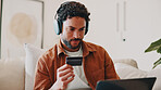 Man, credit card and headphones or laptop on home sofa for streaming music, shopping or subscription. Happy, online movie and person relax on couch with payment, technology and membership purchase