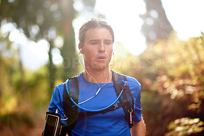Buy stock photo Fitness, man and running in nature with music, exhausted and training challenge for cardio wellness. Runner, earphones and exercise in forest with fatigue, workout podcast and streaming audio on app