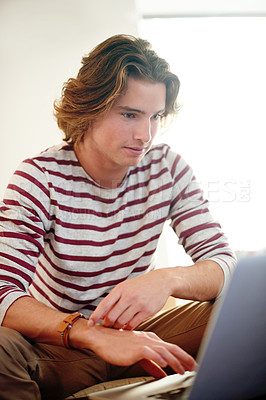 Buy stock photo Laptop, typing and man on sofa for admission, reading and university scholarship email in home. Tech, application and male student in living room for college test research, exam or study assignment
