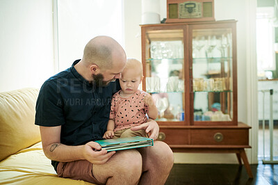 Buy stock photo Dad, baby and reading book in a family home living room for fun. Man or dad with toddler kid on couch for quality time, love and care or learning, talking and together for story or development