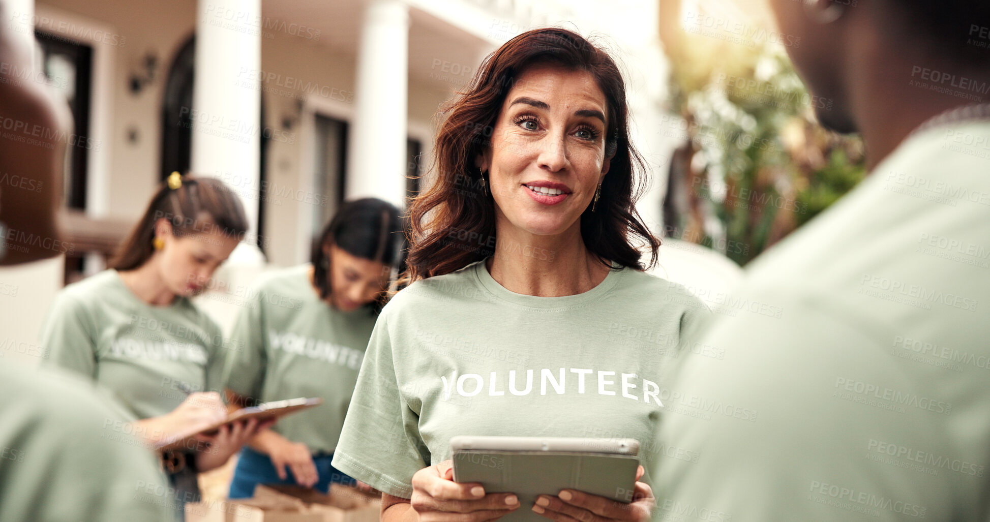 Buy stock photo Woman, team and tablet outdoor for volunteering, sign up and assign tasks for community outreach. Smile, coordinator and people with digital for charity, participation and job allocation for welfare