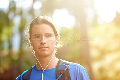 Buy stock photo Fitness, man and portrait with earphones in forest for running podcast, cardio playlist or marathon training. Sunlight, space or trail runner with backpack in woods for wellness or listening to radio