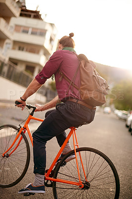 Buy stock photo Morning, back or man on bicycle in city for eco friendly transport, commute or entrepreneur. Outdoor travel, ride or designer on road in urban town with sunrise, fashion or bike for creative career
