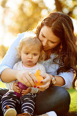 Buy stock photo Mom, child and peeling orange at park with smile, snack or bonding on ground with care, love and diet. Happy people, mother and daughter with citrus fruit, vitamin c and nutrition for growth in Spain