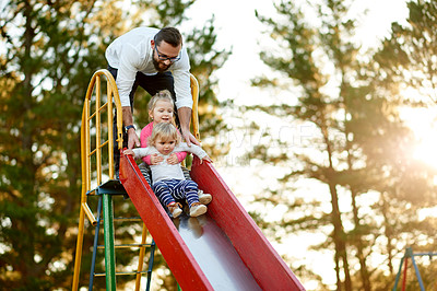 Buy stock photo Nature, slide and father with kids in park for holiday, weekend or vacation together. Smile, trees and girl children with dad for playing outdoor on playground for connection or bonding in summer.