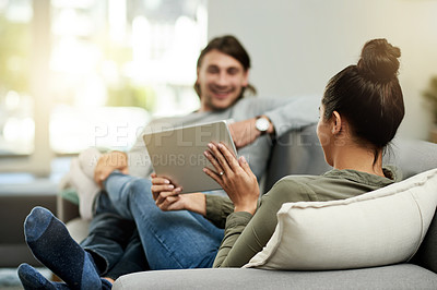 Buy stock photo Conversation, sharing and tablet with couple on sofa in living room of home together for break. App, relax and showing with people talking in apartment for connectivity, browsing or social media