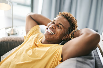 Buy stock photo Portrait, man and stretching on couch, lounge or stress relief in home, happy and calm in apartment. Pride, African person or comfortable on sofa, positive attitude or rest on weekend, smile or break