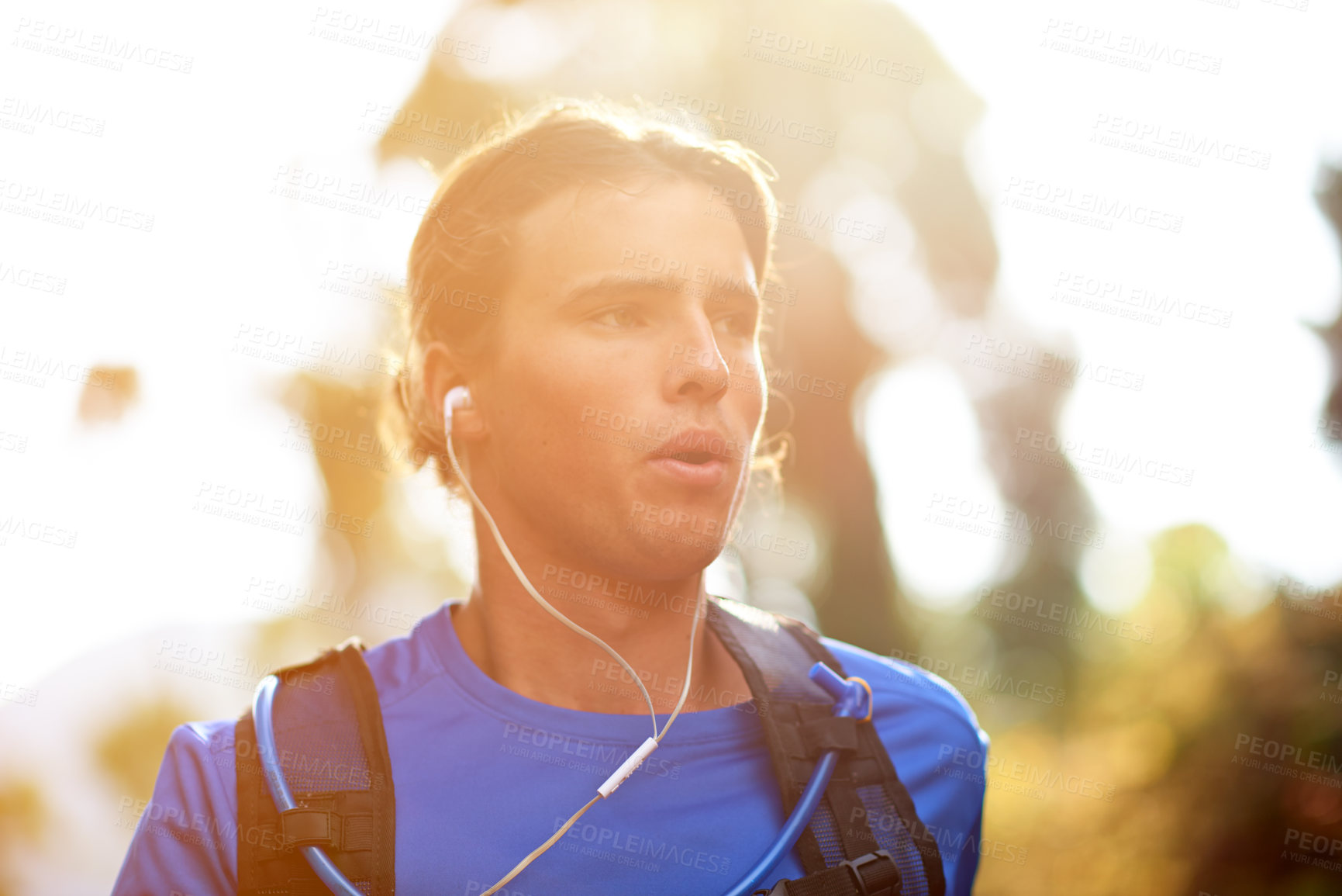Buy stock photo Cardio, training and man in forest, running and energy with breathing, earphones and exercise. Person, outdoor and athlete in woods, listening to music and podcast with challenge, workout or practice
