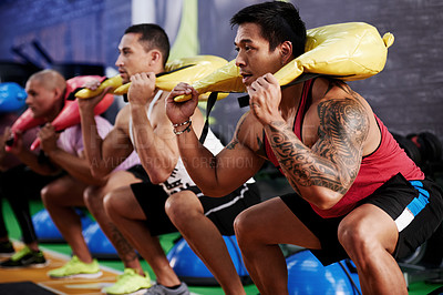 Buy stock photo Class, squat and people with sand bag exercise for training  session, legs workout or core strength. Athletes, teamwork and group of men with weight equipment for fitness, body health or gym support