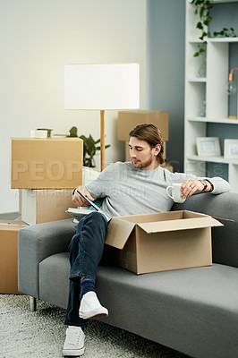 Buy stock photo Homeowner, reading book and man on sofa, relax and boxes with real estate, break and literature. Apartment, property and person on couch, coffee and novel with hobby, relocation and knowledge