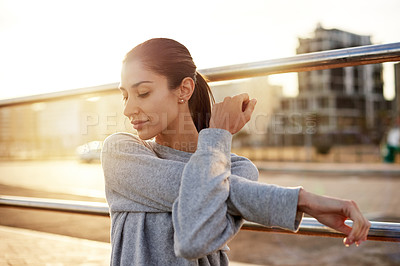 Buy stock photo Fitness, workout and woman stretching in city for healthy body, wellness or prepare for practice at sunset. Warm up arm, outdoor and female runner training, exercise and ready for sports marathon