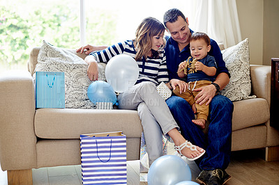 Buy stock photo Birthday, gifts and family with child, lounge and together for first party in house and celebration. Happy, people and pride for toddler growth, man and woman with son in living room, love in home