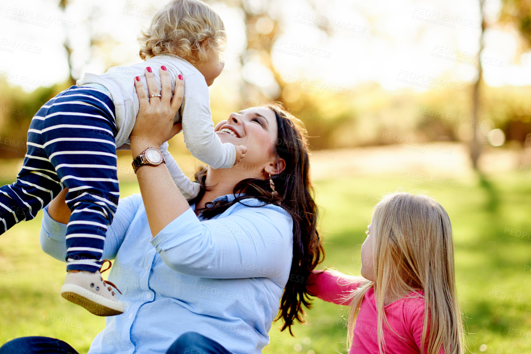 Buy stock photo Fun, children and woman in nature, laugh and playing on summer holiday, bonding and game on weekend. Lifting, daughter or happy mom with kids on break, flare and family at park, bokeh and together