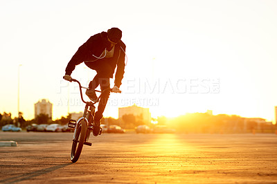 Buy stock photo City, sunset and trick with man on BMX for adrenaline, exercise or extreme sports outdoor. Bike, flare and training with rider on asphalt street in urban town for action, hobby or skill practice