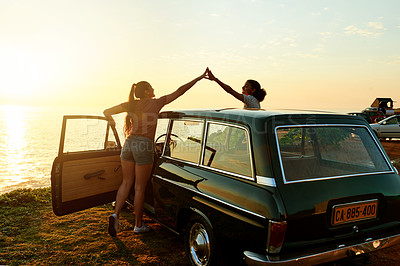 Buy stock photo Shot of two young women giving each other a high five on a road trip