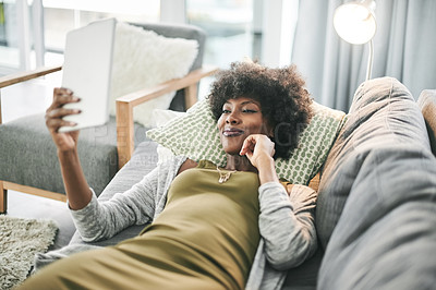 Buy stock photo Woman, smile and relax on sofa with tablet, streaming and laying with movie subscription in home. African person, happy and tech on couch with application, social media or notification at apartment