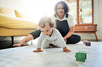 Family, home and baby crawl with mother in living room for growth, relationship and motherhood. Love, child development and happy mom and kid for bonding, quality time and relax together on floor