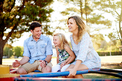 Buy stock photo Playground, parents and child on roundabout for family weekend fun, happy bonding or love. Smile, caring man and woman with daughter on playing equipment together, park visit or support in summer