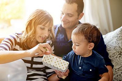 Buy stock photo Parents, child and gift for birthday in house for milestone, celebration and love together in living room. Present, open box and mother with toddler, father and care at party or event in family home