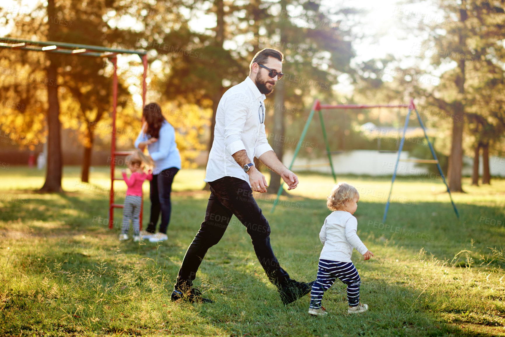 Buy stock photo Playground, playing and parents with children in park for bonding, outdoor games and having fun. Family, sunlight and happy mom, dad and kids on grass for holiday, adventure and activity on weekend