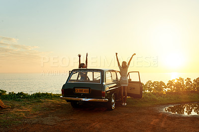 Buy stock photo Shot of two happy young women enjoying a road trip