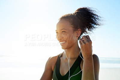 Buy stock photo Fitness, smile and woman with earphones at beach for exercise, music or workout podcast. Space, runner and athlete with tech for marathon training, flare and streaming audio or getting ready by ocean