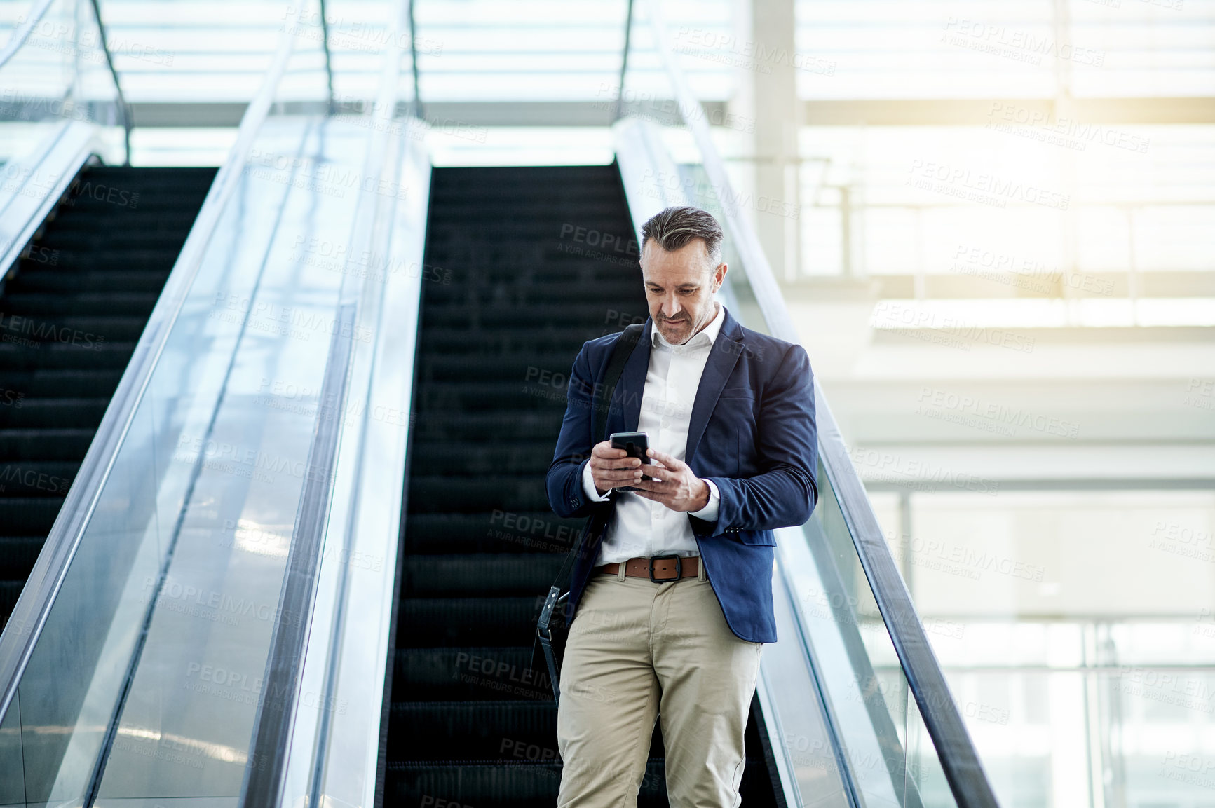 Buy stock photo Escalator, airport and businessman with mobile for travel, commute and arrival in lobby. Conference, mature professional and person on electric stairs on phone for flight schedule, news or trip info