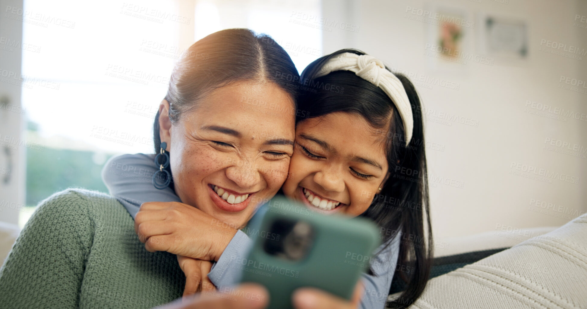 Buy stock photo Phone, mother and child on sofa with hug, laugh and love connection for social media browsing. Asian family, happy mom or kid in home with embrace, relationship affection or online reels with bonding