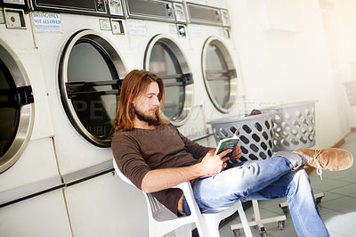 Buy stock photo Man, washing and reading a book in laundry room for cleaning service, knowledge and fabric disinfection. Hygiene, male cleaner and literature novel in laundromat for weekly tasks, hobby and learning