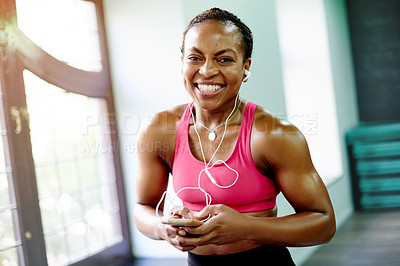 Buy stock photo Black woman, earphones and smile at gym with smartphone, portrait or audio at fitness studio. African girl, phone and listen to music on mobile app, texting or happy at training center in Nigeria
