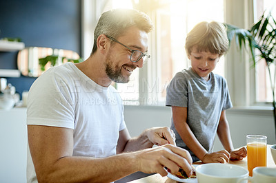 Buy stock photo Breakfast, smile and father with child in kitchen in home with bonding, laughing and wellness. Happy, health and dad with boy kid for eating healthy morning meal together with connection in house.