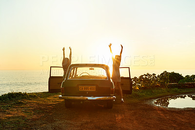 Buy stock photo Shot of two happy young women enjoying a road trip