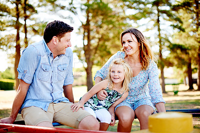 Buy stock photo Playground, parents and child on merry go round for family weekend fun, happy bonding or love. Smile, caring man and woman with daughter on playing equipment together, park visit or support in summer