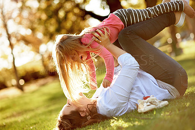 Buy stock photo Mom, girl and lift on grass at park for airplane, bonding or games with smile, flare and outdoor in nature. Happy people, mother and daughter in garden, fun and playful flight on ground in Germany