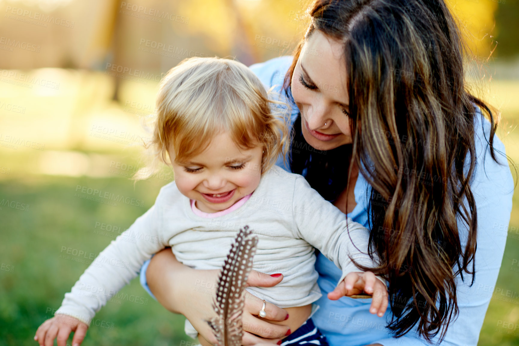 Buy stock photo Outdoor, mother and girl with feather, smile and bonding together with happiness. Family, parent and mama in park, daughter and childhood with weekend break, curious and kid with fun and playing