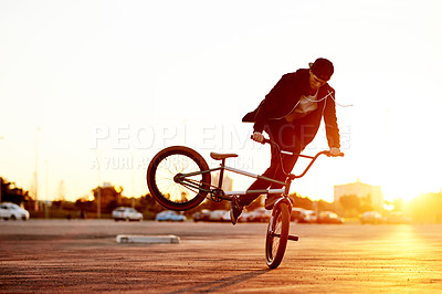 Buy stock photo City, skill and sunset with man on BMX for adrenaline, exercise or extreme sports outdoor. Balance, bike and sunset with rider in parking lot of urban town for action, training or trick practice