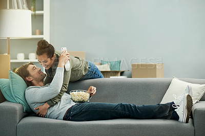 Buy stock photo Movie, popcorn and couple with hug in new home for moving break, property investment and bonding. Love, people and embrace on sofa in dream house with watching tv show, relocation pause or connection