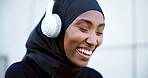 Laugh, fitness and muslim woman with headphones, music streaming or listen to radio with happiness. Hijab, athlete and black person with song playlist, funny and smile on audio break in city outdoor