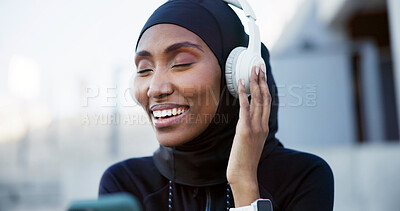 Buy stock photo Music, athlete and muslim woman with phone in city, listen to radio or audio break with smile. Hijab, fitness and happy black person with mobile, headphones or streaming playlist with podcast outdoor
